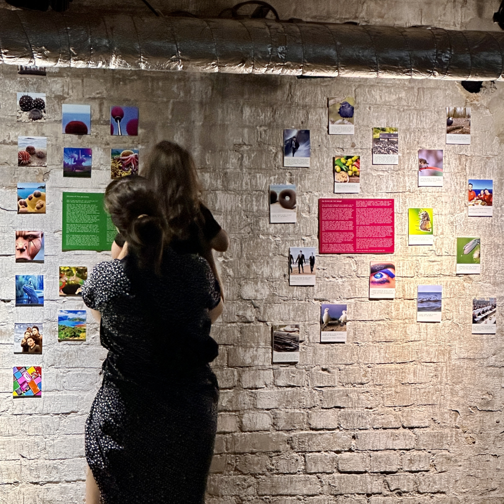 Foto von Prints der AI-Imgs & Texten davor eine Besucherin mit Kind